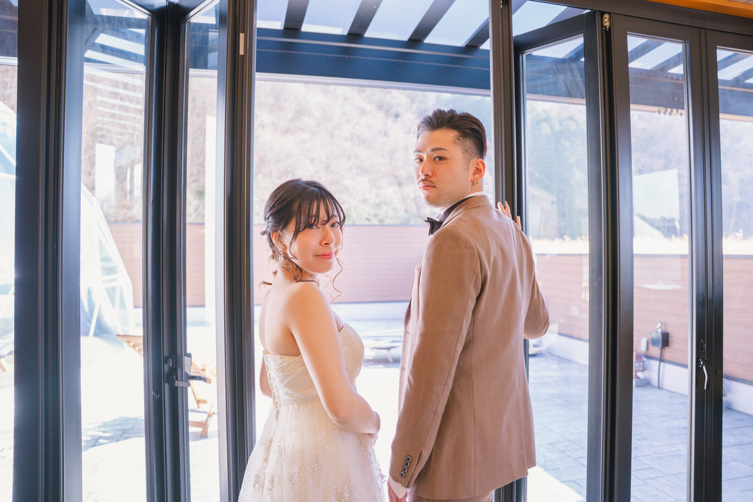 ガラス越しに振り返る新郎新婦
